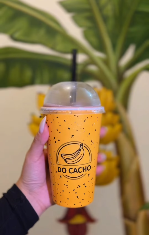 Bebida do Cacho em copo amarelo com o logo da marca